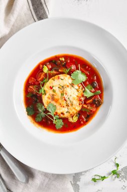 Domates soslu somon balığı keki ve taze yeşillikler. Beyaz kase kırsal masada, kumaşlı. Gurme yemek konsepti