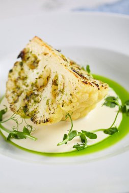 Krema soslu ve soslu kavrulmuş karnabahar. Mavi kumaşlı eski beyaz masa. Lezzetli vejetaryen yemek konsepti