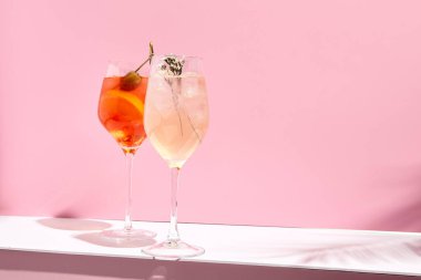 Pembe arka planda Aperol Spritz Kokteyli. Güneş ışığı ve gölge arkaplan. Pembe ve beyaz minimal