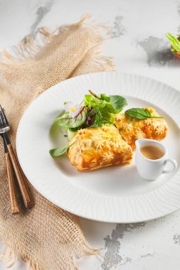 Karaciğer ve krema soslu turta. Taze yeşil yapraklarla süslenmiş. Çuval bezli beyaz tabak.