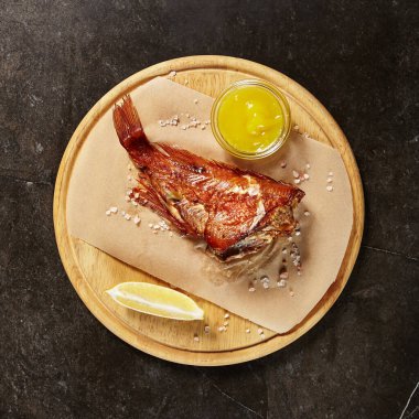 Parşömen ve tahta üzerinde sunulan levrek. Siyah mermer masada kırmızı balık bölümü. Süslü deniz ürünleri yemeği. Restoranın ana yemeği. Nefis bir ziyafet. Gurme yemek servisi.