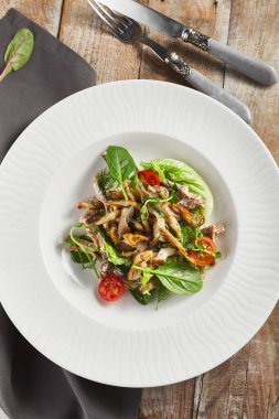 İstiridye mantarı ve et salatası tabağı. Kırsal ahşap masa ve tekstil.