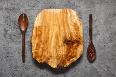 Gri çimento yüzey üst manzarasında Rustik ahşap kesim tahtası. Bıçak kesikli eski mutfak eşyaları. Ahşap ahşap döşeme, kirli beton doku arka planında. Yemek pişirme, mutfak aletleri konsepti