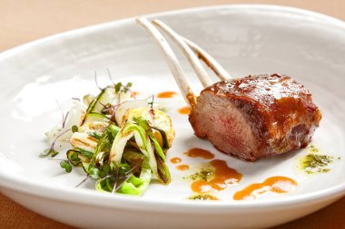 Kuzu pirzolası, beyaz derin tabakta, yakın plan. Lüks restoran ana yemek kenarı manzarası. Havalı yemek kapanışı. Koyun pirzolası. Kasede servis edilen et parçası. Sebze garnitürlü kızarmış et. Aşçılık sanatı