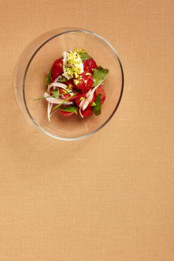 Yuvarlak cam kasede stracciatella ile domatesler. Domates salatası manzaralı. Lüks restoran garnitürü. Şeftali arkaplanlı gurme yemeği kursu. Yemek sunumu sanatı. Güzel yemek.