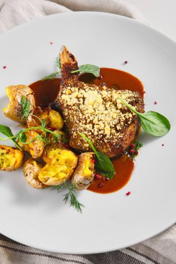 Kızarmış domuz filetosu ve patatesli Demi-Glace. Kaba ahşap masa, kumaş ve taze yeşil ıspanak.