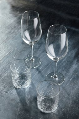 Gri taş masadaki boş bardaklar. Koyu arkaplanda kristal cam.