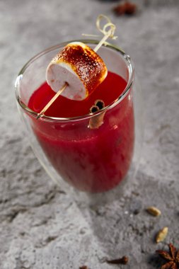 Çubukta kızartılmış marşmelovla ahududu kokteyli. Kaya grisi arkaplanda kırmızı dut