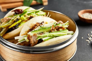 Kızarmış ördekli bao ekmeği. Siyah tahta üzerinde bambu buharı. Çince, Asyaca, otantik gıda konsepti.