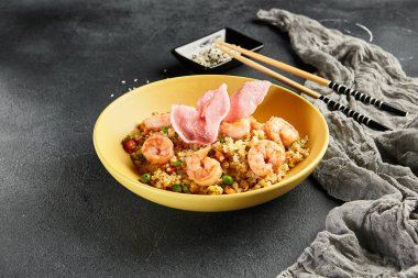 Sebzeli Baharatlı Karides Kızarmış Pirinç. Tahta çubuklu sarı tabak. Koyu renk tahta masa. Çince, Asyaca, otantik gıda konsepti.