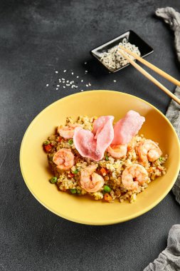 Sebzeli Baharatlı Karides Kızarmış Pirinç. Tahta çubuklu sarı tabak. Koyu renk tahta masa. Çince, Asyaca, otantik gıda konsepti.