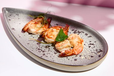 Restoran deniz ürünleri, karides ızgara deniz ürünleri tabağı. Aperatif yemek tabağı beyaz masada, pembe duvarlı. Gün ışığı ve canavar palmiye yapraklarının sert gölgesi. Yaz ya da bahar yemekleri