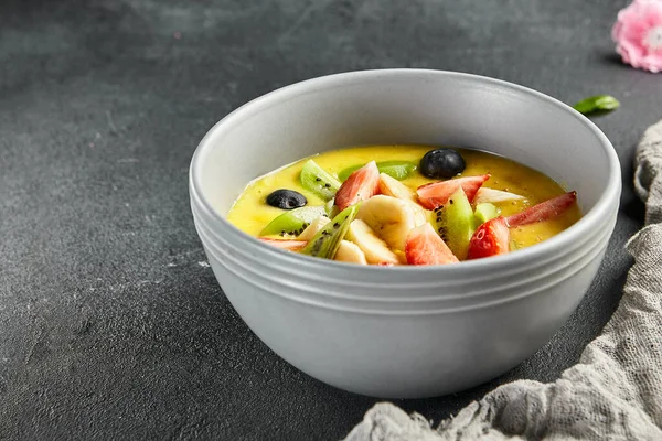 Mango soup with fresh berries and fruits. Asian dessert food on dark slate background. Chinese, asian, authentic food concept.