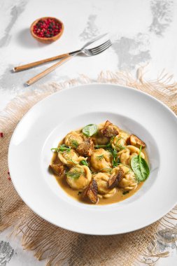 Hamur köftesi Restoran Tabağı. Kremalı Porcini soslu hamur tatlısı. Beyaz masadaki beyaz restoran tabağı. Kırsal restoran yemek konsepti