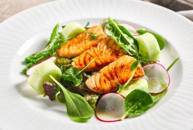 Taze sebzeli somon salatası. Tahta masada sağlıklı balık yemi olan beyaz tabak. Sağlıklı, Vejetaryen, Restoran kırsal gıda konsepti