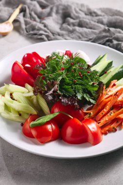 Çiğ yiyecek, taze sebze tabağı. Gri masada sağlıklı organik yiyecekler olan beyaz tabak. Domates, Kereviz, Salatalık ve Turp Sebze ve Taze Yeşiller. Üretim, Sağlıklı, Vejetaryen Kırsal Yemek Konsepti