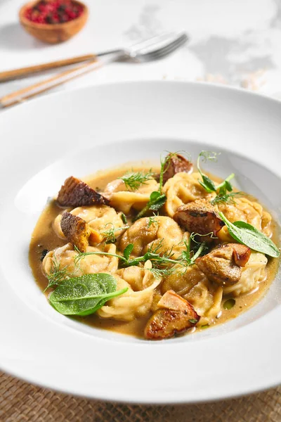 Hamur köftesi Restoran Tabağı. Kremalı Porcini soslu hamur tatlısı. Beyaz masadaki beyaz restoran tabağı. Kırsal restoran yemek konsepti