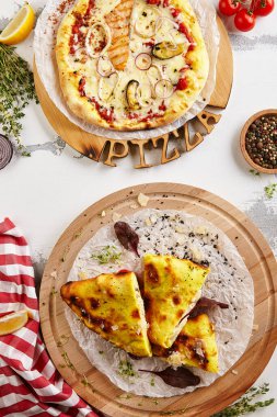 Deniz mahsulleri pizzası ve calzone üst görünümü. Karışık deniz ürünleri, somon, midye ve kalamar. Fesleğen yapraklı tavuk calzone pizza. İçindekiler ve pizza tahtası beyaz masa görünümünde.