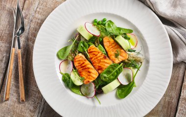 Taze sebzeli somon salatası. Tahta masada sağlıklı balık yemi olan beyaz tabak. Sağlıklı, Vejetaryen, Restoran kırsal gıda konsepti