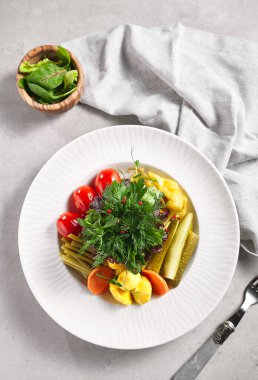 Taze yeşilliklerle turşulu sebze çeşitleri. Turşuyu beyaz tabakta, gri masayı beyaz peçeteyle karıştırdım. Kırsal tarzda yemek konsepti. Üst görünüm