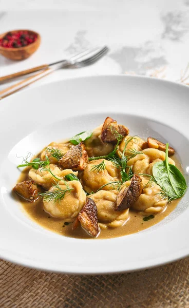 Hamur köftesi Restoran Tabağı. Kremalı Porcini soslu hamur tatlısı. Beyaz masadaki beyaz restoran tabağı. Kırsal restoran yemek konsepti