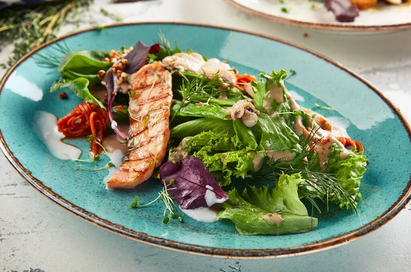 Çıtır karabuğday ve karışık sebzeli deniz ürünleri salatası. Karışık deniz mahsullü Frutti di Mare salatası - somon, kalamar, ahtapot. Mavi tabakta gurme restoran salatası.