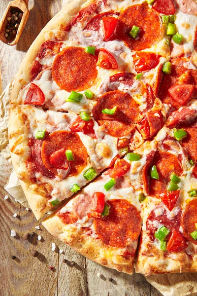 Pizza soslu Pepperoni pizza, mozzarella peyniri ve pepperoni. Tahta üzerinde pizza, ahşap masada malzemelerle.