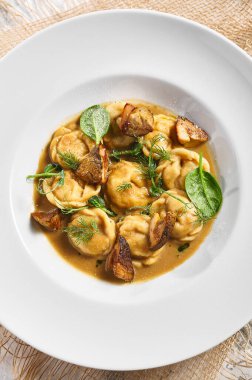 Hamur köftesi Restoran Tabağı. Kremalı Porcini soslu hamur tatlısı. Beyaz masadaki beyaz restoran tabağı. Kırsal restoran yemek konsepti