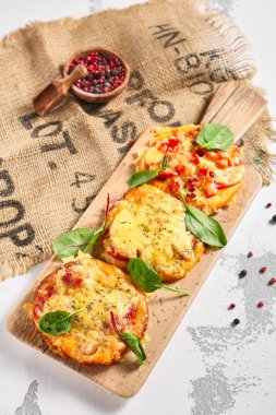 Kırsal beyaz masada mini pizza tahtası. Peynirli pizza ve fesleğen yapraklı domates. Küçük gıda konsepti