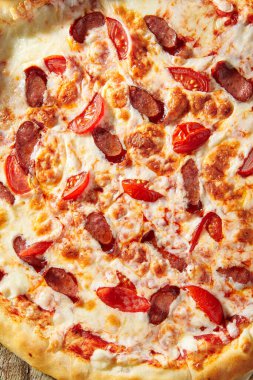 Domatesli baharatlı İtalyan sosisli pizza, mozzarella peyniri, sosis dilimi. Ev yapımı pizza ve ahşap masa üzerinde yemek malzemeleri. Fast food mu abur cubur mu? Pizza üstü mü?