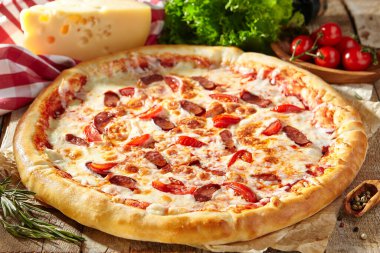 Domatesli baharatlı İtalyan sosisli pizza, mozzarella peyniri, sosis dilimi. Ev yapımı pizza ve ahşap masa üzerinde yemek malzemeleri. Fast food ya da abur cubur pizza.