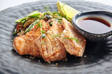 Teppanyaki stili somon - Soya soslu ızgara somon fileto ve sebze. Limon ve yeşil fasulye yaprağıyla süslenmiş Japon Teppanyaki Somon Bifteği. Siyah Asya plakası yakın görünüm