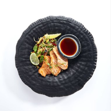 Teppanyaki stili somon - Soya soslu ızgara somon fileto ve sebze. Limon ve yeşil fasulye yaprağıyla süslenmiş Japon Teppanyaki Somon Bifteği. Beyaz arkaplan görünümlü siyah Asya plakası