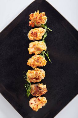 Gunkan Suşi, Gunkan Maki Suşi, deniz ürünleri ve baharatlı sos. İçinde pirinç olan suşi ve Norveç yosunu sarılmış. Siyah tabakta lezzetli Gunkan suşisi. Beyaz arka planda izole edilmiş. Üst görünüm 