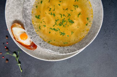 Geleneksel Bowling Yemeği - Siyah Masada Tavuk Erişte Çorbası. Koyu dokulu arka planda seramik kasede çorba ve yiyecek malzemeleri.