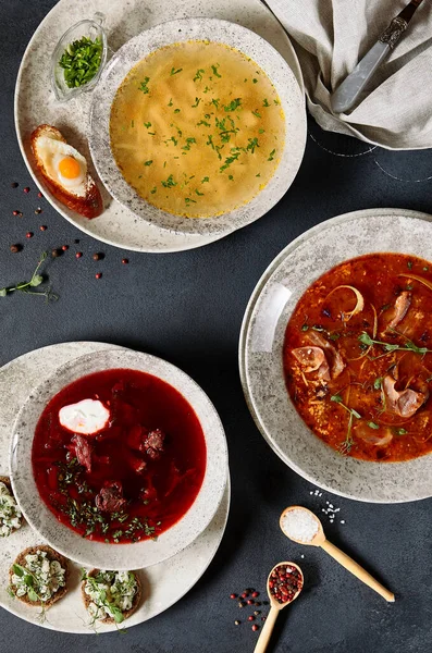 スープセット チキン ヌードルスープ ボルシチ ビーツスープ とソラヤンカ スパイシーで酸味のあるスープ 暗い素朴なテーブルの上に夕食を設定します トップビュー フラットレイアウト — ストック写真