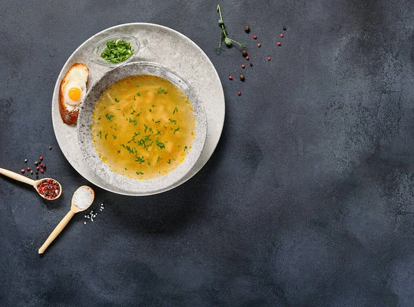 Geleneksel Bowling Yemeği - Siyah Masada Tavuk Erişte Çorbası. Koyu dokulu arka planda seramik kasede çorba ve yiyecek malzemeleri.
