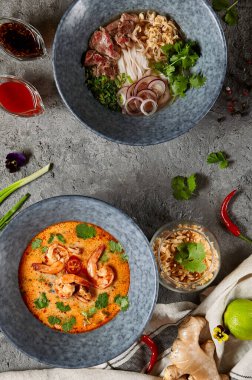 Asya mutfağı - Tayland mutfağı Tom Yam çorbası ve Vietnam Pho Bo çorbası. Karides Deniz Ürünleri Baharatlı Çorbası ve Vietnam Bifteği ve Erişte. Otantik yemek takımı.