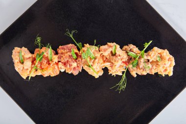 Gunkan Suşi, Gunkan Maki Suşi, deniz ürünleri ve baharatlı sos. İçinde pirinç olan suşi ve etrafına Norveç yosunu sarılmış. Siyah tabakta lezzetli Gunkan suşisi. Beyaz arkaplanda izole