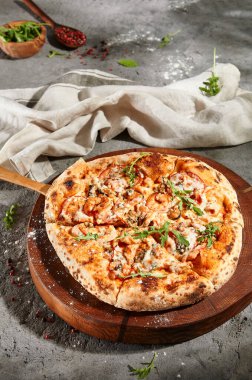 İtalyan Deniz Ürünleri Pizzası - Ahşap tabakta karışık deniz mahsullü pizza. Gri zemin üzerinde kırsal deniz ürünleri pizzası. Güneş ışığı ve sert gölge.