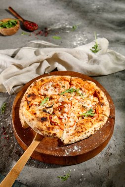 İtalyan Deniz Ürünleri Pizzası - Ahşap tabakta karışık deniz mahsullü pizza. Gri zemin üzerinde kırsal deniz ürünleri pizzası. Güneş ışığı ve sert gölge.