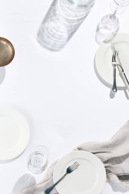 Beyaz masa örtülü restoran ya da kafe masası manzarası. Boş kafeterya masası. Güneş ışığı ve yukarıdan sert gölge manzaralı. Kafe konseptinde yaz günü. Kristal beyaz arkaplan