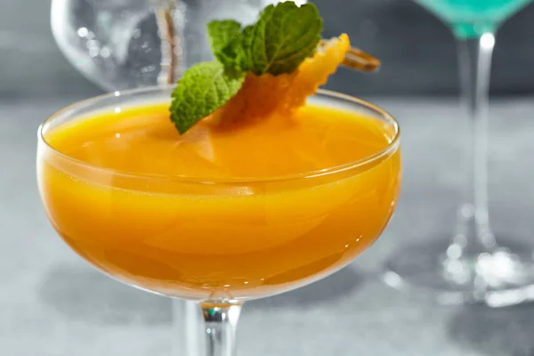 鸡尾酒加伏特加和芒果夏日鸡尾酒的概念与阳光和阴影 用薄荷叶和橙皮装饰的鸡尾酒 — 图库照片