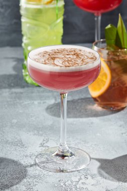The Clover Club Cocktail is a cocktail consisting of gin, lemon juice, raspberry syrup, and egg white. Red Clover Club Cocktail with white foam and cinnamon powder. Vintage table,  sunshine and shadow clipart