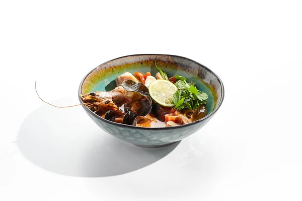 Tom yum or tom yam - hot and sour Thai soup with mixed seafood. Thai traditional soup with shrimps and coconut milk. Tom yum on white background. Isolated soup plate over white background.