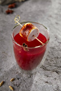 Çubukta kızartılmış marşmelovla ahududu kokteyli. Kaya grisi arkaplanda kırmızı dut