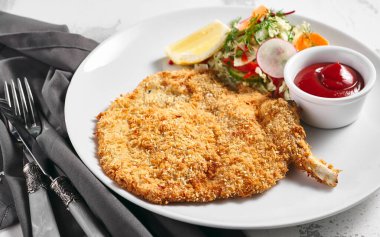 Salata, limon ve soslu şnitzel tavuk tabağı. Beyaz masada tavuk veya domuz eti Alman fast food 'u
