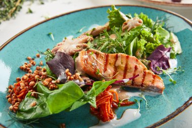 Çıtır karabuğday ve karışık sebzeli deniz ürünleri salatası. Karışık deniz mahsullü Frutti di Mare salatası - somon, kalamar, ahtapot. Mavi tabakta gurme restoran salatası.