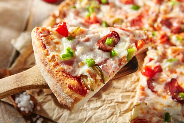 比萨餐厅菜单 羊皮纸上的肉比萨 顶部是热香肠和意大利辣香肠片 木制餐桌 配上披萨配料 强烈阴影下的阳光 质朴的 自然的食物 — 图库照片