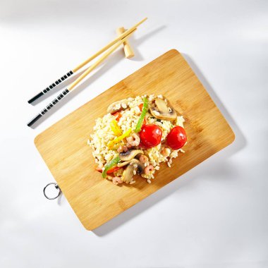 Sebzeli kızarmış tavuk pilavı. Beyaz arka planda Asya tarzı yemekler. Çubuklu ahşap tabak. Üst görünüm